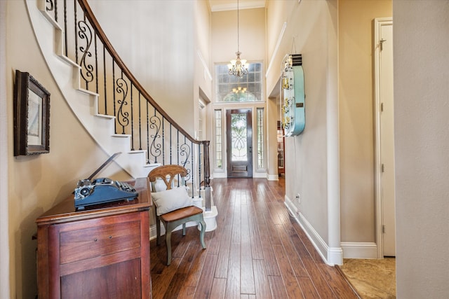 entrance foyer featuring hardwood / wood-style flooring, a chandelier, a high ceiling, and crown molding