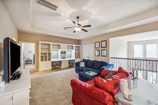 carpeted living room with a tray ceiling and ceiling fan