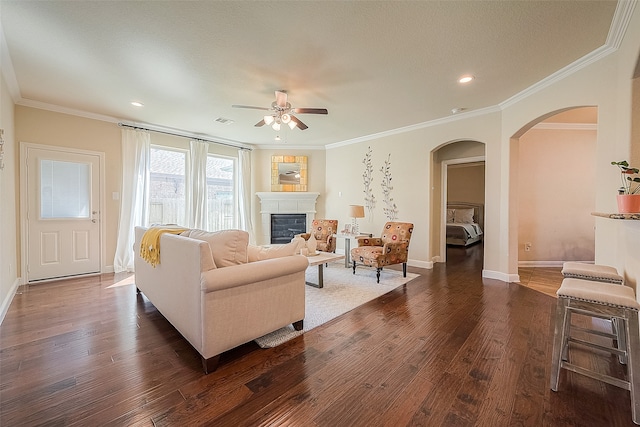 living room with ornamental molding, ceiling fan, and dark wood-type flooring