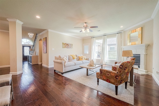 living room with a textured ceiling, ornamental molding, ceiling fan, and dark wood-type flooring