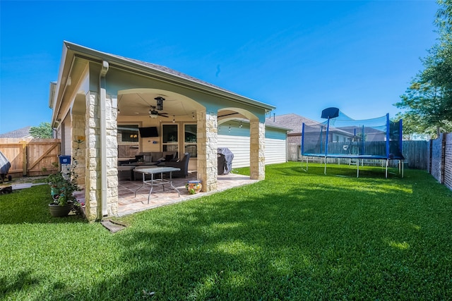 back of house with ceiling fan, a trampoline, a yard, and a patio area