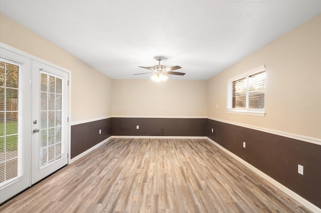 empty room with ceiling fan, light hardwood / wood-style flooring, and french doors