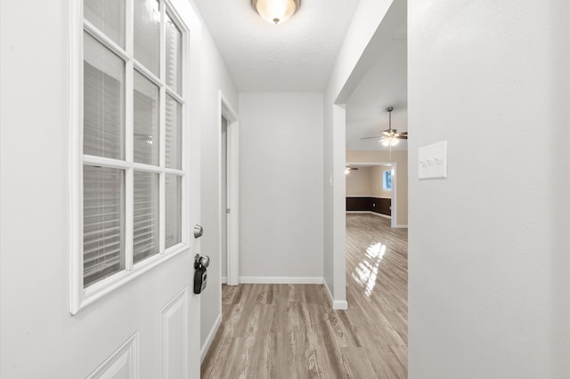 hall with a textured ceiling and light hardwood / wood-style floors