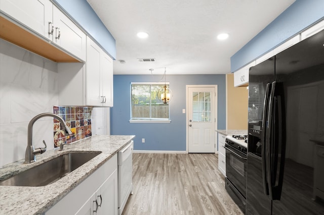 kitchen with black appliances, white cabinetry, sink, and pendant lighting