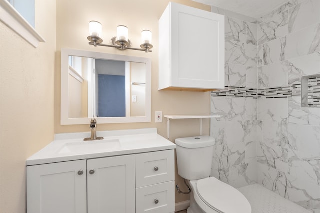 bathroom with vanity, toilet, and tiled shower