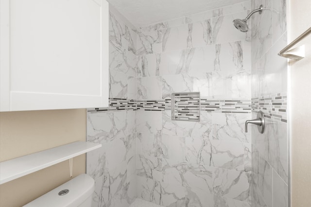 bathroom featuring toilet and tiled shower