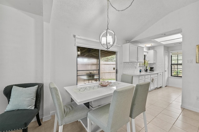 tiled dining space with a textured ceiling, lofted ceiling, an inviting chandelier, and a wealth of natural light