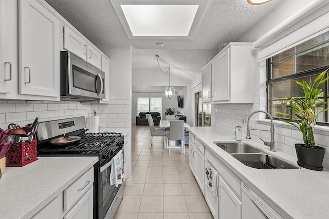 kitchen with a textured ceiling, sink, stainless steel appliances, and white cabinets