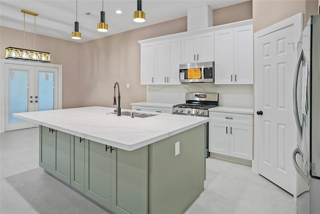 kitchen with white cabinets, a kitchen island with sink, stainless steel appliances, and hanging light fixtures