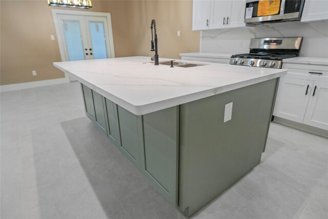 725 A Ave, La Marque, TX 77568 - kitchen featuring appliances with stainless steel finishes, a center island with sink, white cabinetry, light stone counters, and french doors