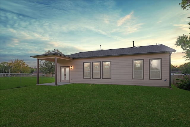 back house at dusk featuring a yard and a patio area