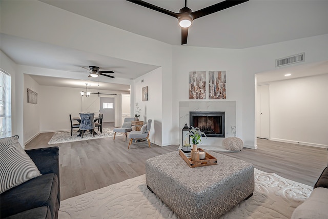 living room with a premium fireplace, light wood-type flooring, and ceiling fan