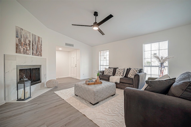 living room with light hardwood / wood-style floors, a high end fireplace, ceiling fan, and plenty of natural light