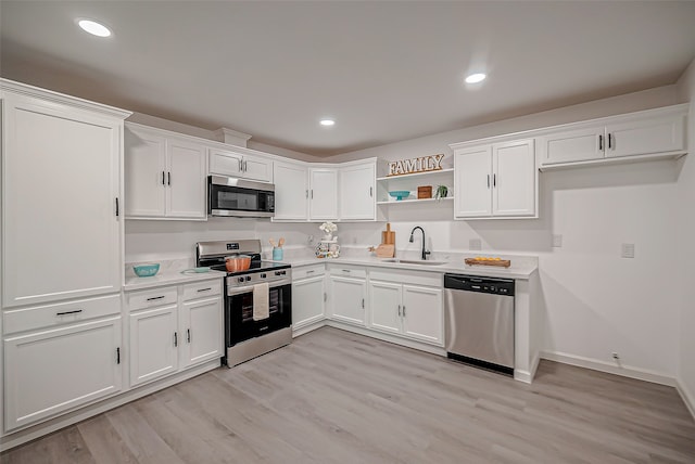 kitchen with appliances with stainless steel finishes, light wood-type flooring, white cabinetry, and sink