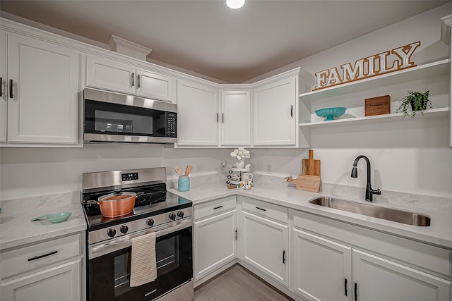 kitchen featuring appliances with stainless steel finishes, white cabinetry, sink, and light hardwood / wood-style flooring