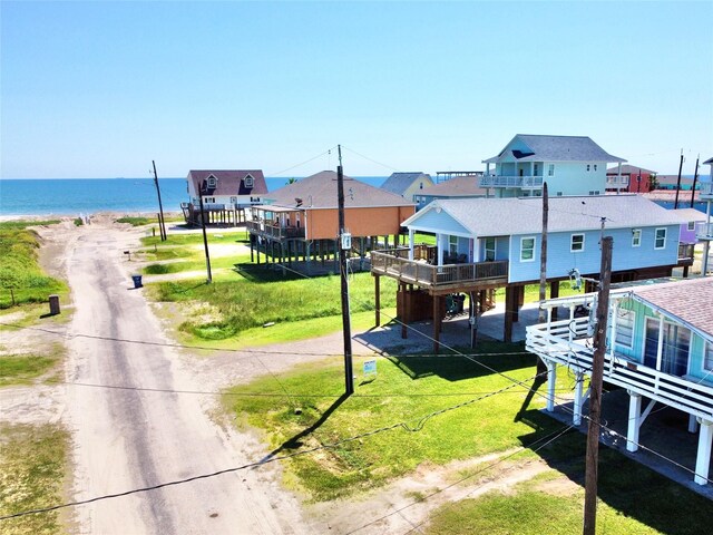 view of property's community with a lawn, a beach view, and a deck with water view