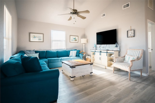 living room featuring ceiling fan, high vaulted ceiling, and light hardwood / wood-style flooring