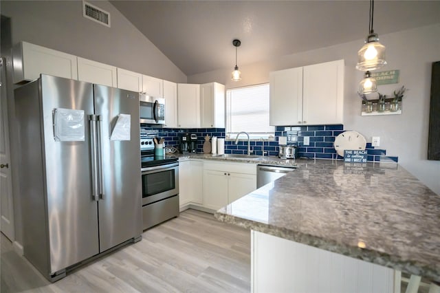 kitchen featuring sink, white cabinetry, stainless steel appliances, decorative backsplash, and decorative light fixtures