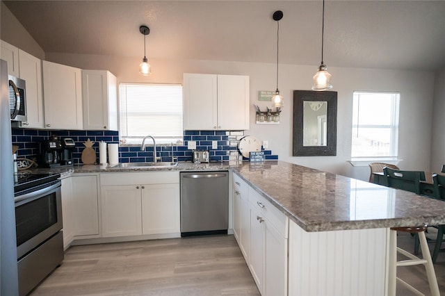 kitchen featuring pendant lighting, sink, appliances with stainless steel finishes, white cabinets, and kitchen peninsula