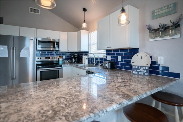 kitchen with appliances with stainless steel finishes, decorative light fixtures, sink, white cabinets, and light stone countertops