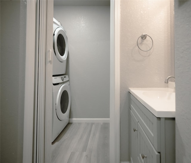 laundry room with stacked washer / dryer, sink, and light hardwood / wood-style flooring