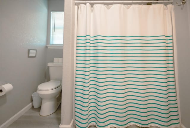 bathroom featuring toilet and curtained shower