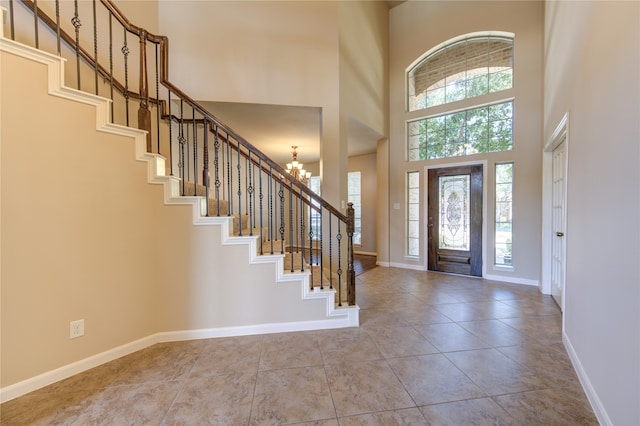 foyer with light tile patterned floors, an inviting chandelier, a high ceiling, and a healthy amount of sunlight