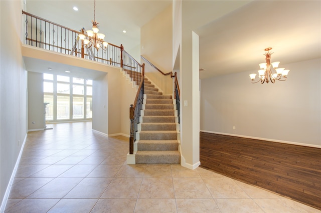 staircase with a notable chandelier, a towering ceiling, and hardwood / wood-style flooring