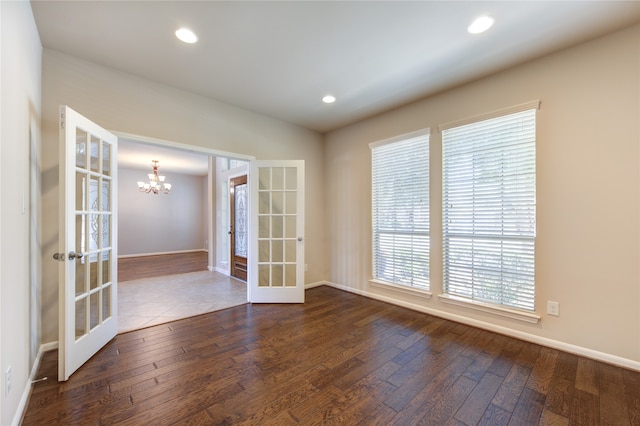 spare room featuring a chandelier, french doors, and dark hardwood / wood-style flooring