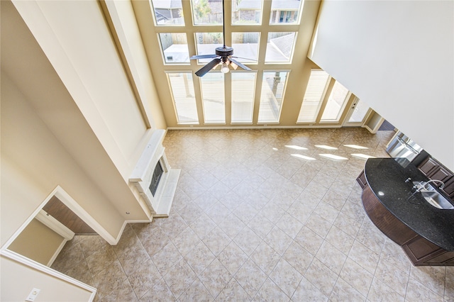 unfurnished living room featuring a towering ceiling, ceiling fan, and light tile patterned floors