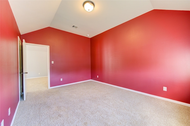 carpeted spare room with vaulted ceiling