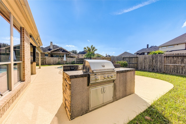 view of patio with area for grilling, a fenced in pool, and an outdoor kitchen