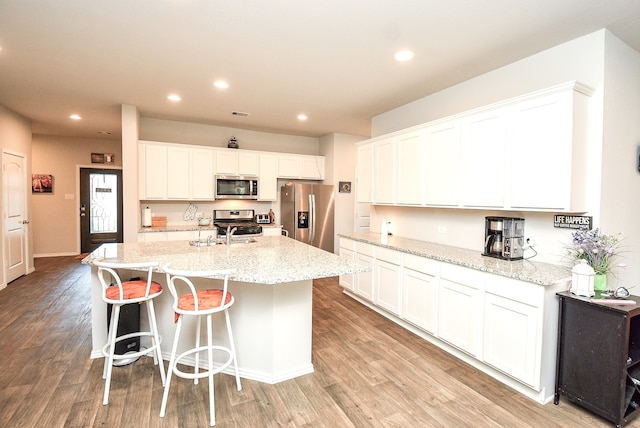 kitchen with stainless steel appliances, white cabinetry, and light wood-type flooring