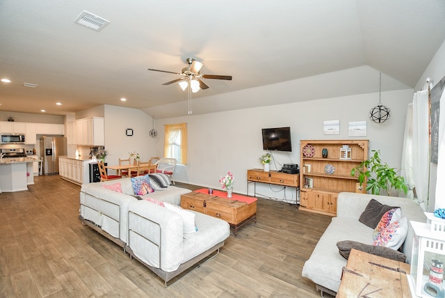 living room featuring vaulted ceiling, ceiling fan, and light hardwood / wood-style flooring