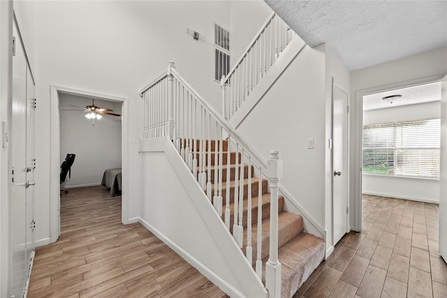 stairs featuring wood-type flooring and ceiling fan