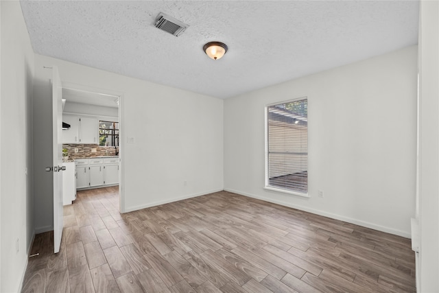 interior space featuring a textured ceiling, light hardwood / wood-style floors, and multiple windows