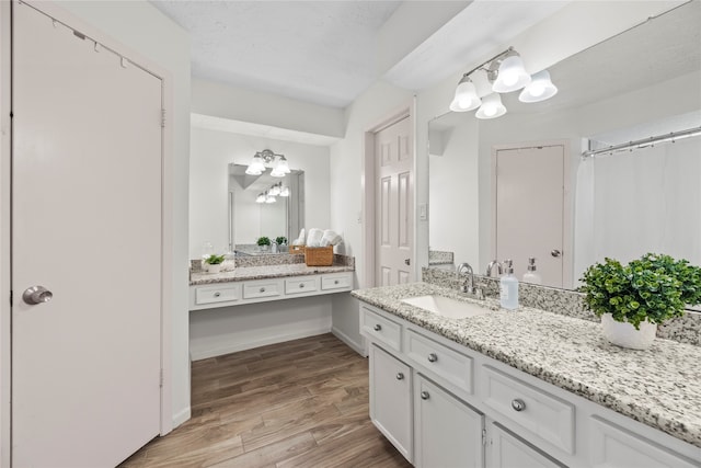 bathroom with an inviting chandelier, vanity, and hardwood / wood-style flooring