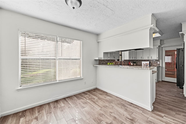 kitchen with light hardwood / wood-style flooring, a wealth of natural light, and kitchen peninsula