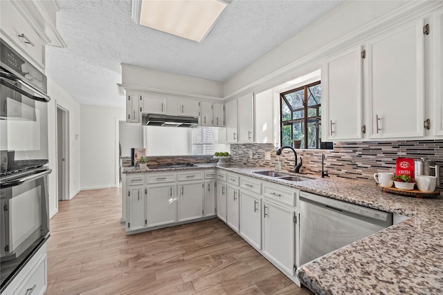 kitchen with white cabinets, dishwasher, sink, and a textured ceiling