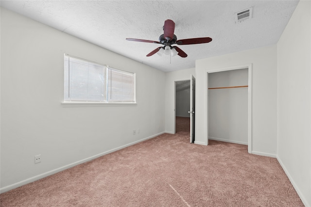 unfurnished bedroom with ceiling fan, light colored carpet, a textured ceiling, and a closet