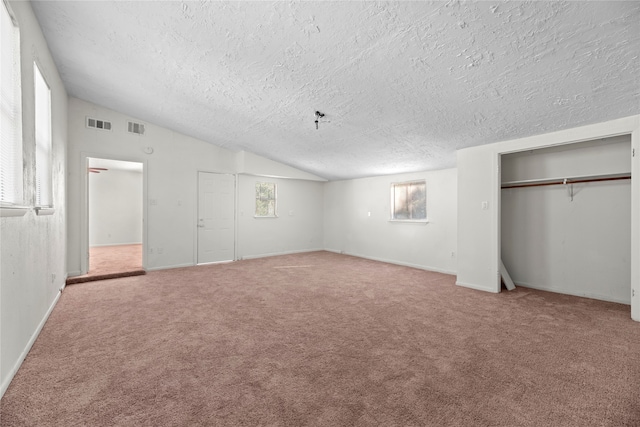 unfurnished bedroom with lofted ceiling, a textured ceiling, and carpet floors