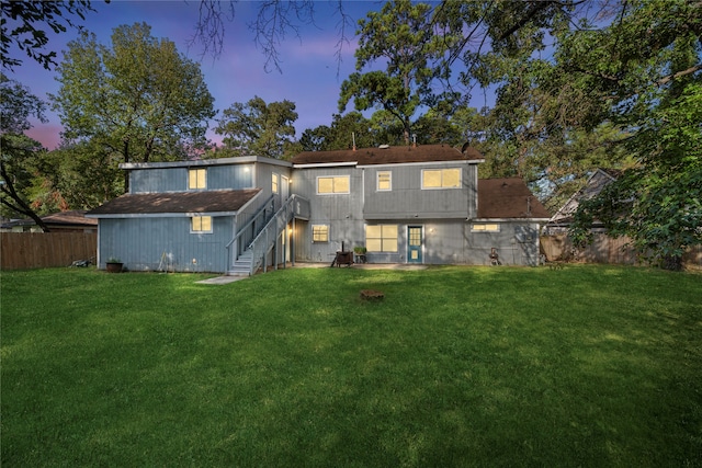 back house at dusk with a lawn