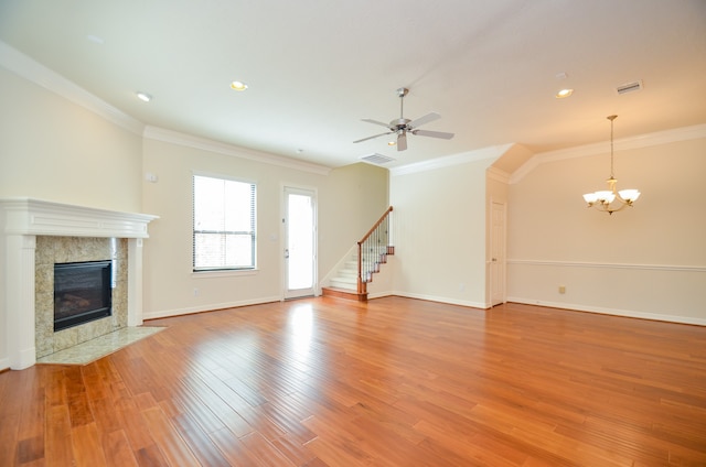 unfurnished living room featuring ceiling fan with notable chandelier, crown molding, a high end fireplace, and hardwood / wood-style flooring