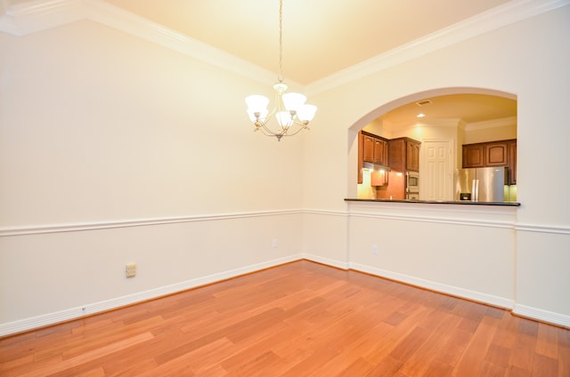 spare room with ornamental molding, a chandelier, and light hardwood / wood-style floors