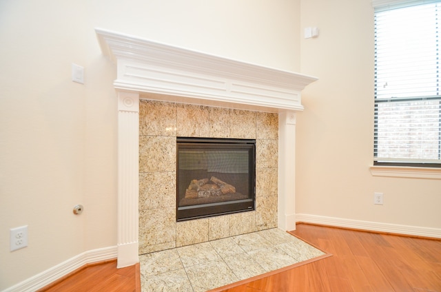 interior details with a tiled fireplace and hardwood / wood-style floors