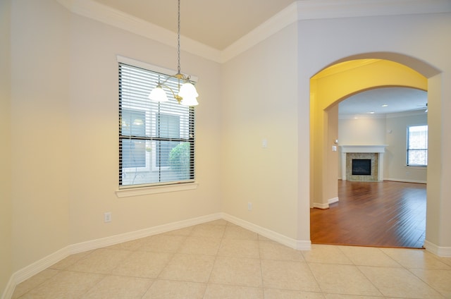 empty room with ornamental molding, light hardwood / wood-style floors, a fireplace, and an inviting chandelier