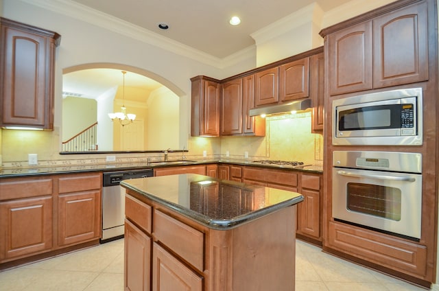 kitchen featuring appliances with stainless steel finishes, a kitchen island, crown molding, sink, and a notable chandelier