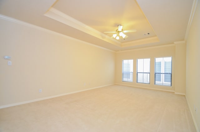 carpeted empty room with a raised ceiling, ornamental molding, and ceiling fan