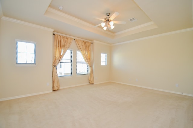 empty room featuring ceiling fan, a tray ceiling, plenty of natural light, and light carpet