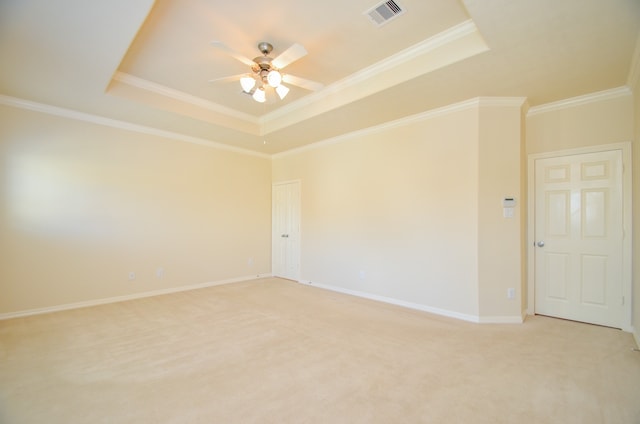 carpeted spare room with ceiling fan, a tray ceiling, and crown molding